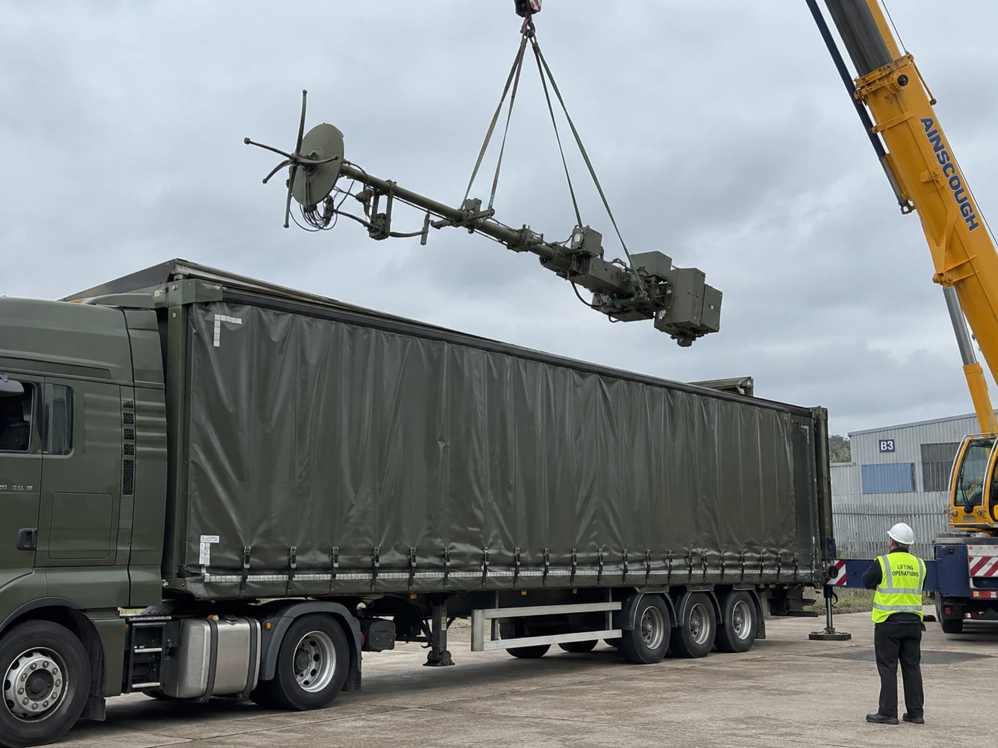 Antenne manutentionnée par grue à travers le toit ouvert d’un camion bâché