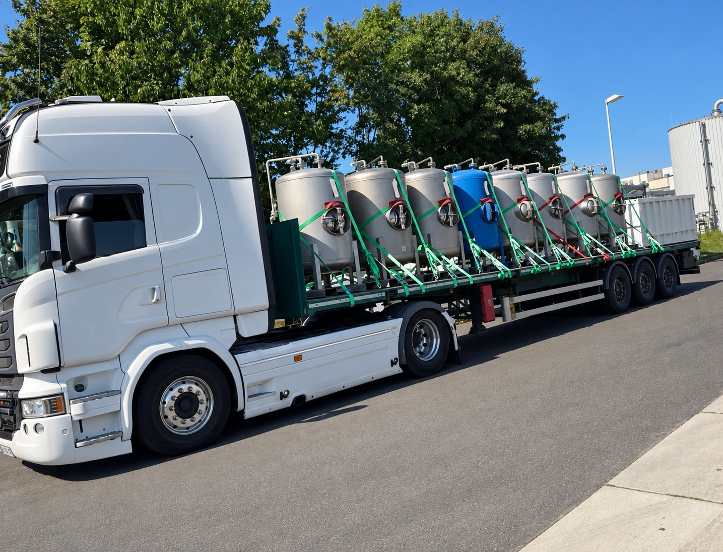 Camion plateau DTI chargé de cuves industrielles correctement sanglées